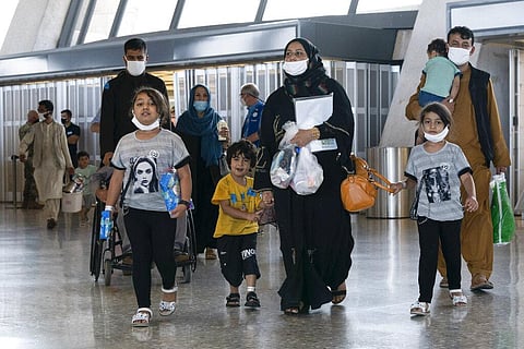 Poeple evacuated from Kabul, Afghanistan, walk through the terminal before boarding a bus after they arrived at Washington Dulles International Airport. (Photo | AP)