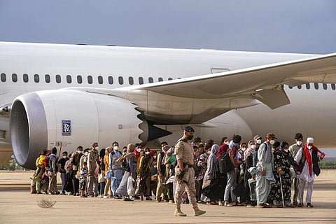 Afghan people who were transported from Afghanistan, walk after disembarking a plane, at the Torrejon military base as part of the evacuation process in Madrid. (Photo | AP)