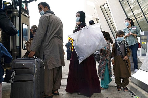 Children accompanied by their families evacuated from Kabul, Afghanistan, board a bus after they arrived at Washington Dulles International Airport, in Chantilly, Va., on Friday, Aug. 27 (Photo | AP)