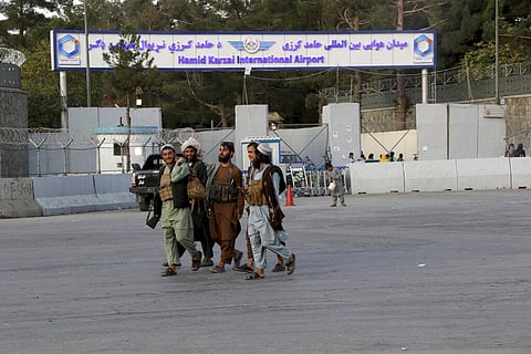 Taliban fighters walk in front of the gate of Hamid Karzai international Airport in Kabul, Afghanistan. (Photo | AP)