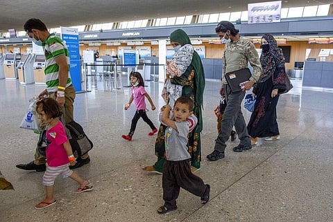Families evacuated from Kabul, Afghanistan, walk through the terminal to board a bus after they arrived at Washington Dulles International Airport. (Photo | AP)