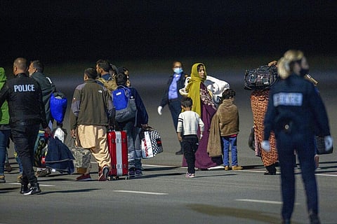 Police officers escort families evacuated from Kabul, Afghanistan. (Photo | AP)