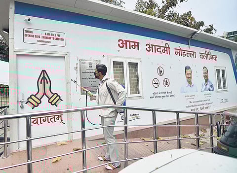 A worker sprays disinfectants on a mohalla clinic. (File Photo | PTI)