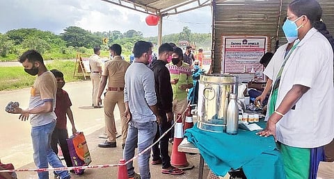 Passengers from Kerala waiting at Chavadi on the Tamil Nadu side of the Walayar border on Tuesday to undergo RT-PCR tests