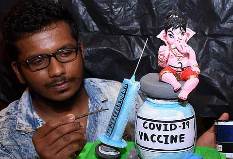 An artiste gives finishing touches to a  Ganesh idol promoting Covid-19 vaccination in Mysuru. (Photo | Udayshankar S, EPS)