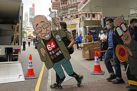 Police officers take away cutout of picture of the late founding chairman of the Hong Kong Alliance in Support of Patriotic Democratic Movements of China. (Photo | AP)
