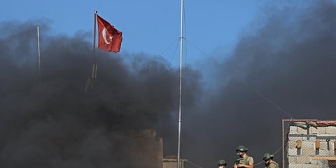 Turkish soldiers stand guard atop an outpost as smoke billows from burning tyres during a demonstration in Syria's northwestern province of Idlib. (File photo| AFP)