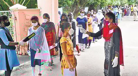 NEET aspirants undergo thermal scanning before entering a exam centre in Karimnagar on Sunday.