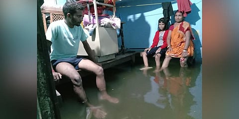 Members of a family sit in their house in knee-deep water. (Photo | Express)