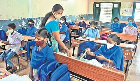 A teacher inspects the book of a student at Musheerabad High School, in Hyderabad on Wednesday. (Photo | S Senbagapandiyan)