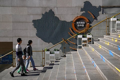 A family walks by a map showing Evergrande development projects in China at an Evergrande city plaza in Beijing. (Photo| AP)
