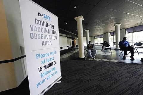Students, faculty, staff and community residents sit socially-distanced from each other after receiving an injection of either the Pfizer or Moderna COVID-19 vaccine. (Photo | AP)