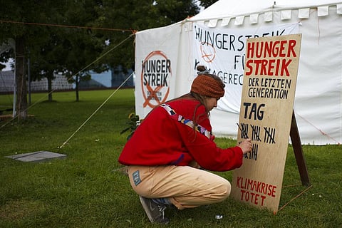 Climate activist Carla Hinrichs makes a line on a wooden board to count the days a small camp of climate activists have been in a hunger strike. (Photo | AP)