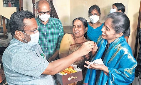 Revenue Minister K Rajan presents sweets to K Meera, who secured the sixth rank, at her residence in Thrissur on Friday | Express