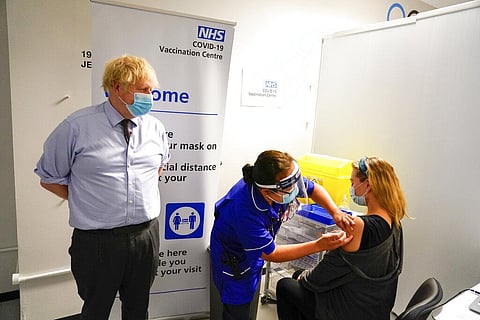 Britain's Prime Minister Boris Johnson, left watches as a woman receive her COVID-19 vaccine, as he visits a vaccination center in London. (Photo | AP)