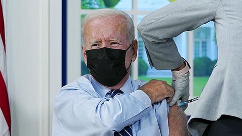President Joe Biden receives a COVID-19 booster shot during an event in the South Court Auditorium on the White House campus. 