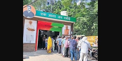 Daily wage labourers stand in a queue to get food at the Jan Rasoi.