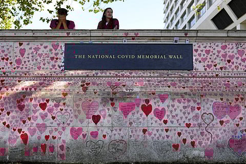 Nurses from the nearby hospital rest atop the National Covid Memory Wall in London. (Photo | AP)