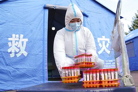 In this photo released by China's Xinhua News Agency, a worker in protective clothing handles COVID-19 test samples in Bayan County of Harbin city in northeastern China's Heilongjiang. (Photo | AP)