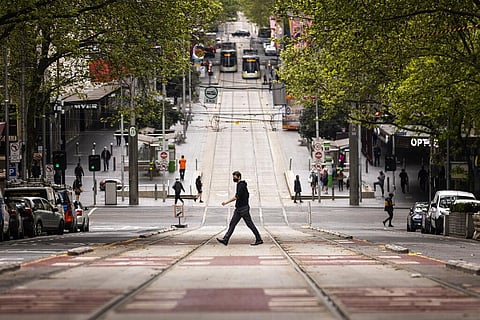 A man wearing mask crosses Bourke Street in Melbourne. (Photo | AP)