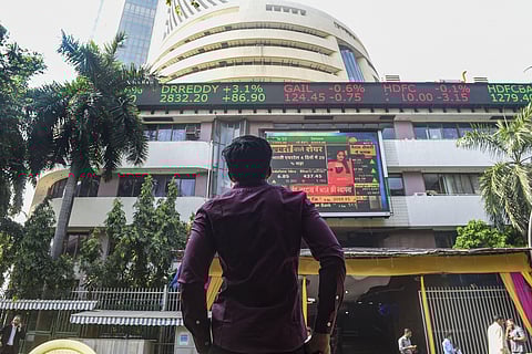 A bystander watches the stock prices displayed on a digital screen at the facade of the Bombay Stock Exchange building in Mumbai. (File photo | PTI)