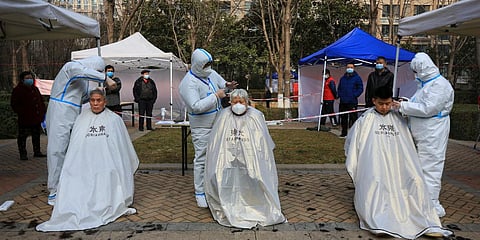 Hairdressers wearing protected suits cut residents' hair at a block which has become under lockdown in Xi'an in northwest China. (Photo| AP)