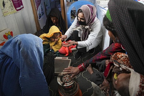 A nurse checks the weight of a child in a makeshift clinic organized by World Vision at a settlement near Herat, Afghanistan, Dec. 16, 2021. (Photo | AP)