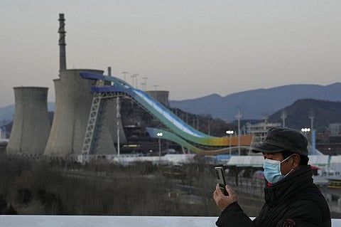 A resident wearing a mask takes photos near the Big Air Shougang, a venue for freestyle and snowboard big air events at the Beijing Winter Olympic Games. (Photo | AP)