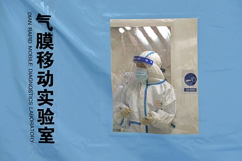 A worker wearing protective equipment stands inside a temporary COVID-19 testing laboratory in northern China's Tianjin Municipality, Tuesday, Jan. 11, 2022. (Photo | AP)