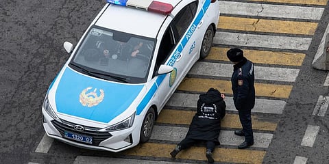 A police officer watches over a man as his papers are checked by colleagues at a crossing. (Photo | AP)