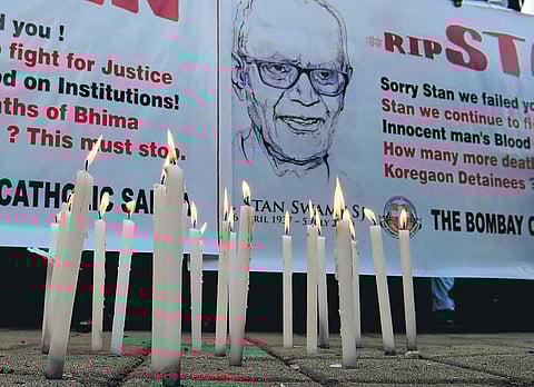 People hold posters next to candles outside a church holding memorial mass for Stan Swamy in Mumbai. (File Photo | PTI)