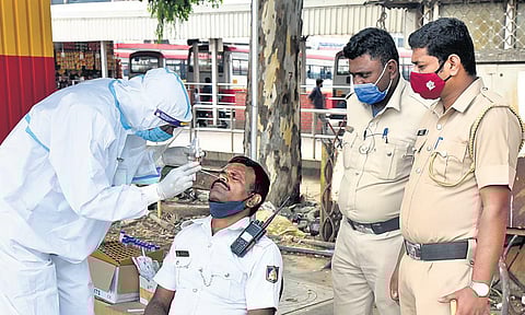 A health worker collects a swab sample of a traffic policeman in  Bengaluru on Thursday | Express