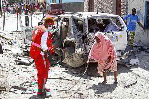 A woman, right, points a medical worker to remains of the suicide bomber at the scene, after Somalia's government spokesperson Mohamed Ibrahim Moalimuu was wounded in a suicide bombing.(Photo | AP)