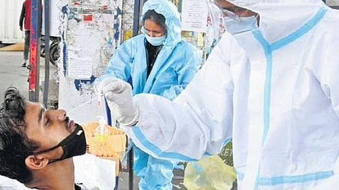 A health worker collects swab samples of a man in Bengaluru on Saturday.  The city saw 22,284 fresh Covid-19 cases