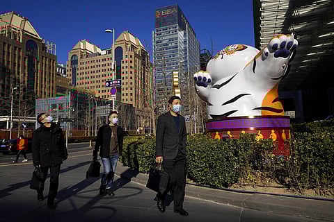 People wearing face masks walk by a gestured tiger statue, a Chinese zodiac which marks the year 2022, on display at the Central Business District in Beijing, Monday, Jan. 17, 2022. (Photo | AP)
