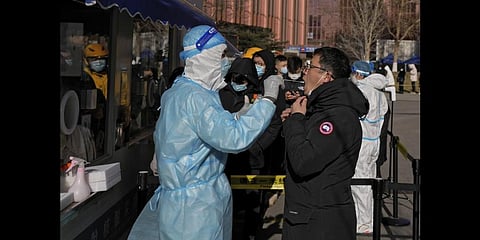 A man gets a swab for the COVID-19 test to meet traveling requirements at a mobile coronavirus testing facility outside a commercial office buildings in Beijing, Sunday, Jan. 16, 2022.(Photo | AP)
