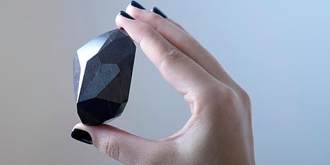 An employee of Sotheby's Dubai presents a 555.55 Carat Black Diamond 'The Enigma' to be auctioned at Sotheby's Dubai gallery, in Dubai, United Arab Emirates, Monday, Jan. 17, 2022. (Photo | AP)