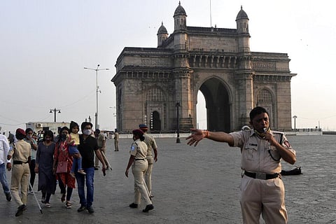 An India policeman asks visitors to vacate the area around Gateway of India amid restrictions imposed due to rising numbers of COVID-19 cases. (Photo | AP)