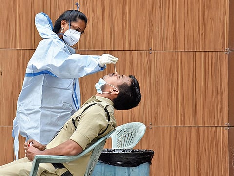 A health staffer collecting sample from a police official for Covid test in Vijayawada on Wednesday | P Ravindra Babu