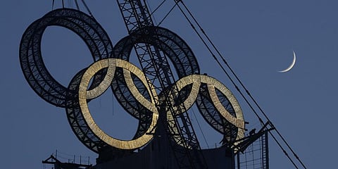 A worker labours to assemble the Olympic Rings onto of a tower on the outskirts of Beijing, China on Jan. 5, 2022.(Photo | AP)