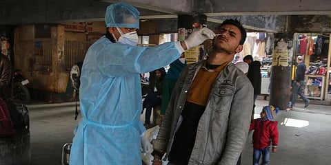 A health worker collects a swab sample from a passenger to test for COVID-19 at a bus station in Jammu. (Photo | AP)