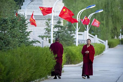 Monks walk along a sidewalk path lined with Chinese flags at the Tibetan Buddhist College near Lhasa in western China's Tibet Autonomous Region(File Photo | AP)
