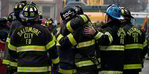Firefighters embrace each other after a deceased firefighter was pulled out of a building collapse while battling a two-alarm fire in a vacant row home in Baltimore. (Photo | AP)