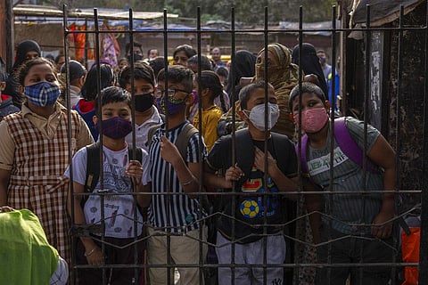 Students wearing masks wait at the gate of a school to attend classes in Dharavi, one of Asia's largest slums,Mumbai, India, Monday, Jan. 24, 2022. (Photo | AP)