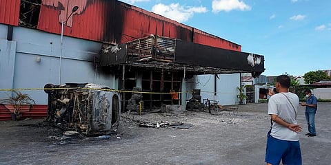 A man stands outside of a torched nightclub after two groups clashed in Sorong, West Papua province, Indonesia. (Photo | AP)