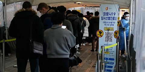 A medical worker moves to guide people as they wait for their coronavirus test at a makeshift testing site in Seoul, South Korea. (Photo | AP)
