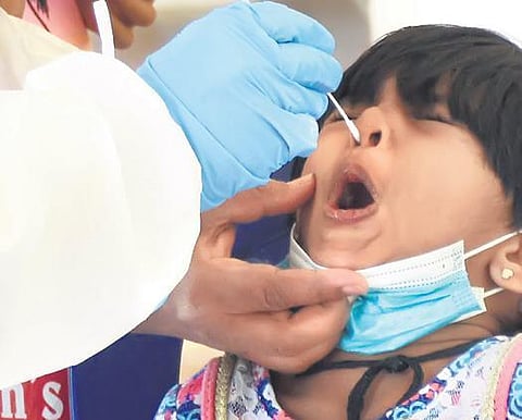A Health department staffer collecting swab samples from a child in Mysuru