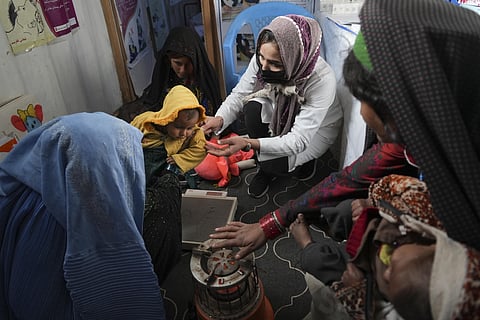 FILE - A nurse checks the weight of a child in the makeshift clinic organized by World Vision at a settlement near Herat, Afghanistan, on Dec. 16, 2021. (Photo | AP)