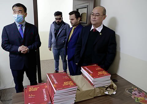 Chinese lecturer, Zhiwei Hu, left, teachers and officials of the Chinese Language Department stand in front of Chinese language books intended for students in Salahaddin University in Irbil, Iraq.
