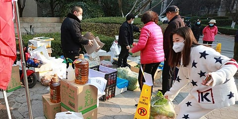 Residents shop for food at a temporary food store set up to serve residents outside a residential block after the suspension of delivery services in Xi'an.  (Photo | AP)